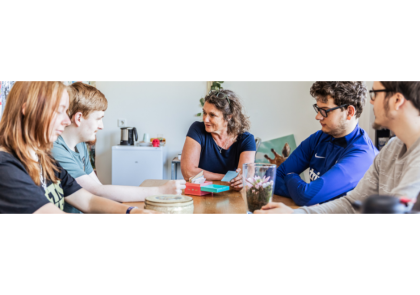 Vrouw zit met jongeren om tafel te praten